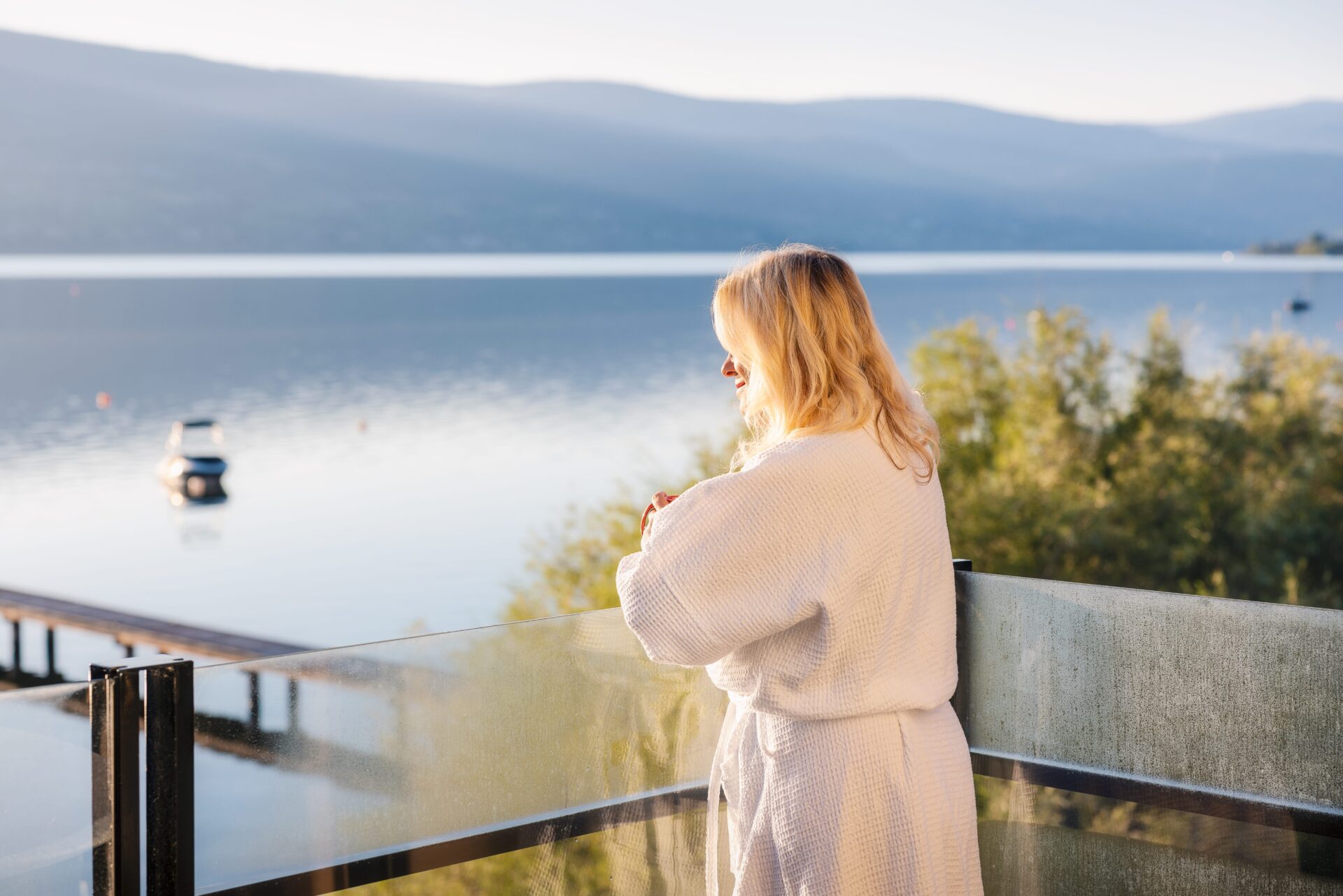 Woman looking out over the lake from her private balcony at Summerland Waterfront Resort & Spa
